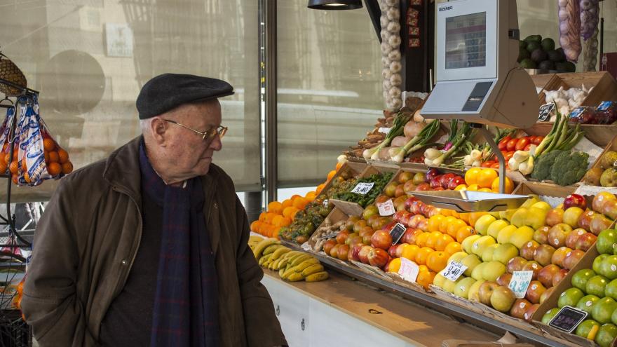 Señor mayor comprando en un puesto de fruta