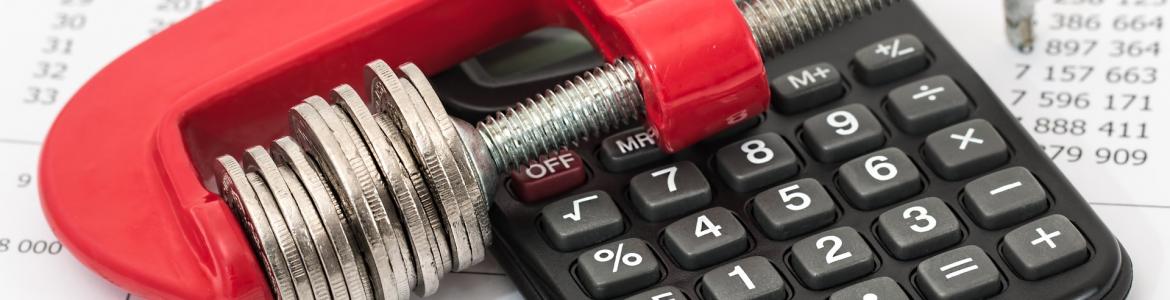 Expedientes de Regulación de Empleo (EREs) Imagen de monedas sujetas con un tornillo de presión sobre calculadora