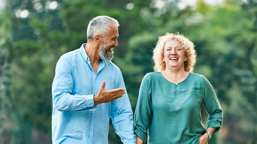 Pareja de mediana edad paseando por el bosque sonrientes