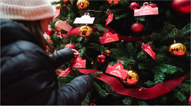 Una niños sujetando el adorno de un árbol de navidad